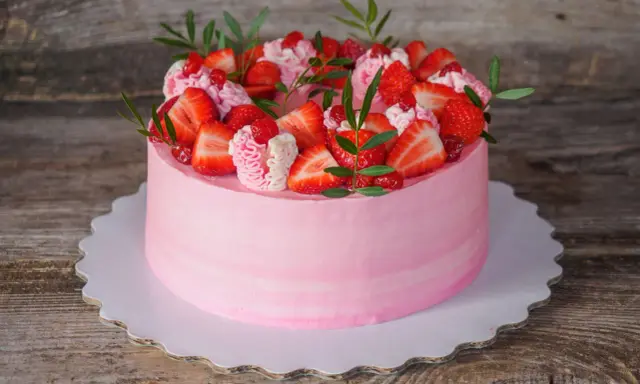 Un délicieux gâteau fraise anniversaire rose, orné de fruits frais et de crème, prêt à célébrer un moment spécial.