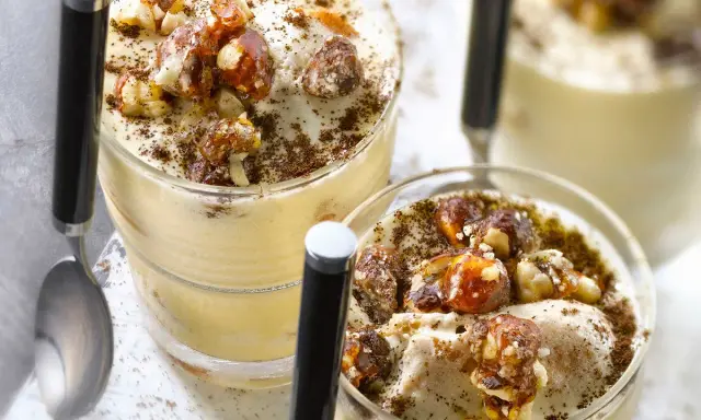 Deux verrines de tiramisu noisette, garnies de noisettes caramélisées et saupoudrées de cacao.