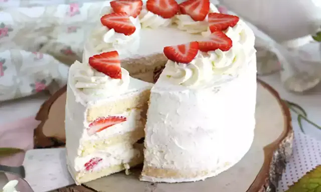 Un délicieux layer cake fraise, garni de crème fouettée et de fraises fraîches, prêt à être dégusté.