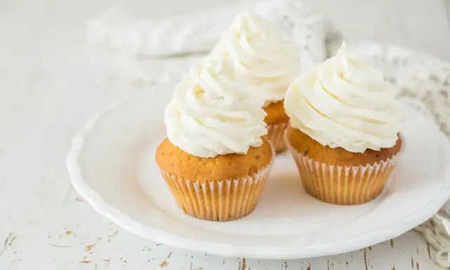 Trois cupcakes sur une assiette blanche, ornés d'un généreux glacage cupcake vanille.