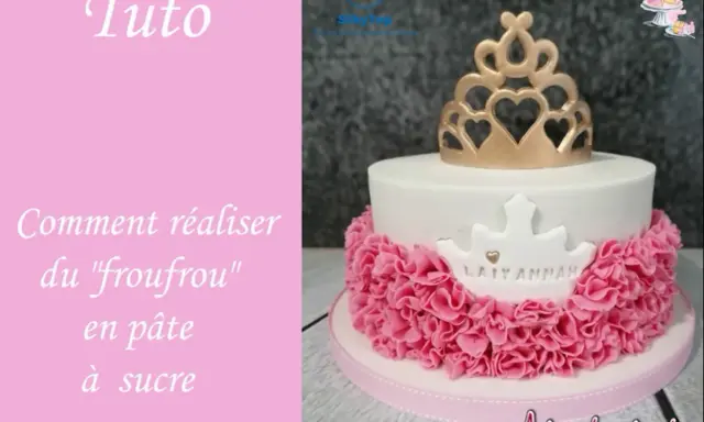 Gâteau d'anniversaire en pâte à sucre blanc orné d'une couronne dorée et d'un "froufrou" rose.