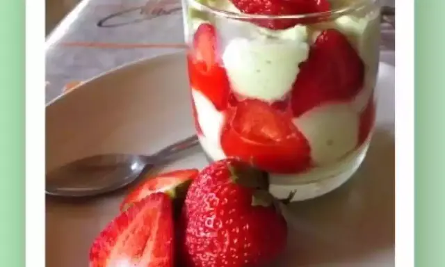 Un délicieux tiramisu pistache fraise, présenté en verrine avec des fraises fraîches sur le côté.