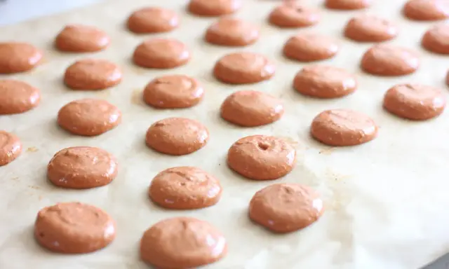 Des petites **collerettes macaron** marron clair, prêtes à être enfournées pour devenir de délicieux macarons.