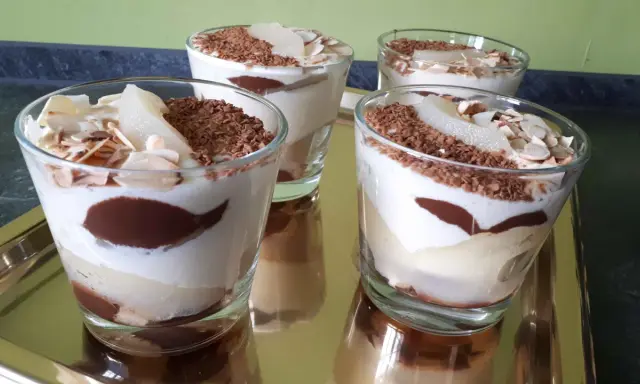 Quatre verrines poire chocolat mascarpone, garnies de copeaux de chocolat et d'amandes effilées, sur un plateau doré.