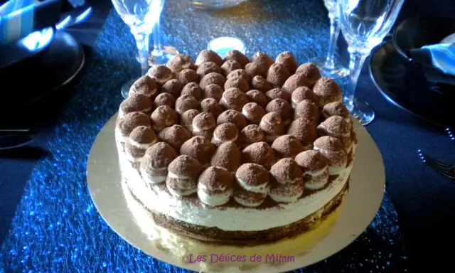 Un délicieux tiramisu revisité, parsemé de cacao, trône sur une table bleue scintillante, prêt à être dégusté.
