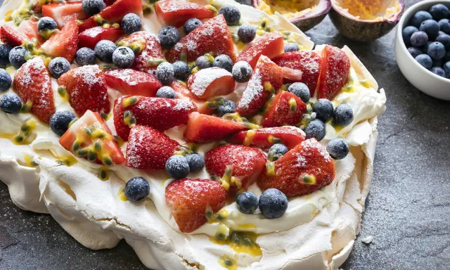 Pavlova inratable garnie de fraises, myrtilles et fruits de la passion. Un délice croustillant à l'extérieur et moelleux à l'intérieur.