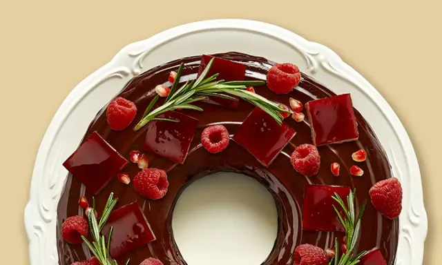 Gâteau angel cake au chocolat, décoré de framboises, de gelée rouge et de romarin.