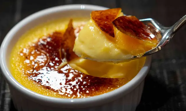 Une cuillère de crème brûlée, parfaite pour savoir que faire avec 4 jaunes d'œufs. La croûte caramélisée craque sous la cuillère.