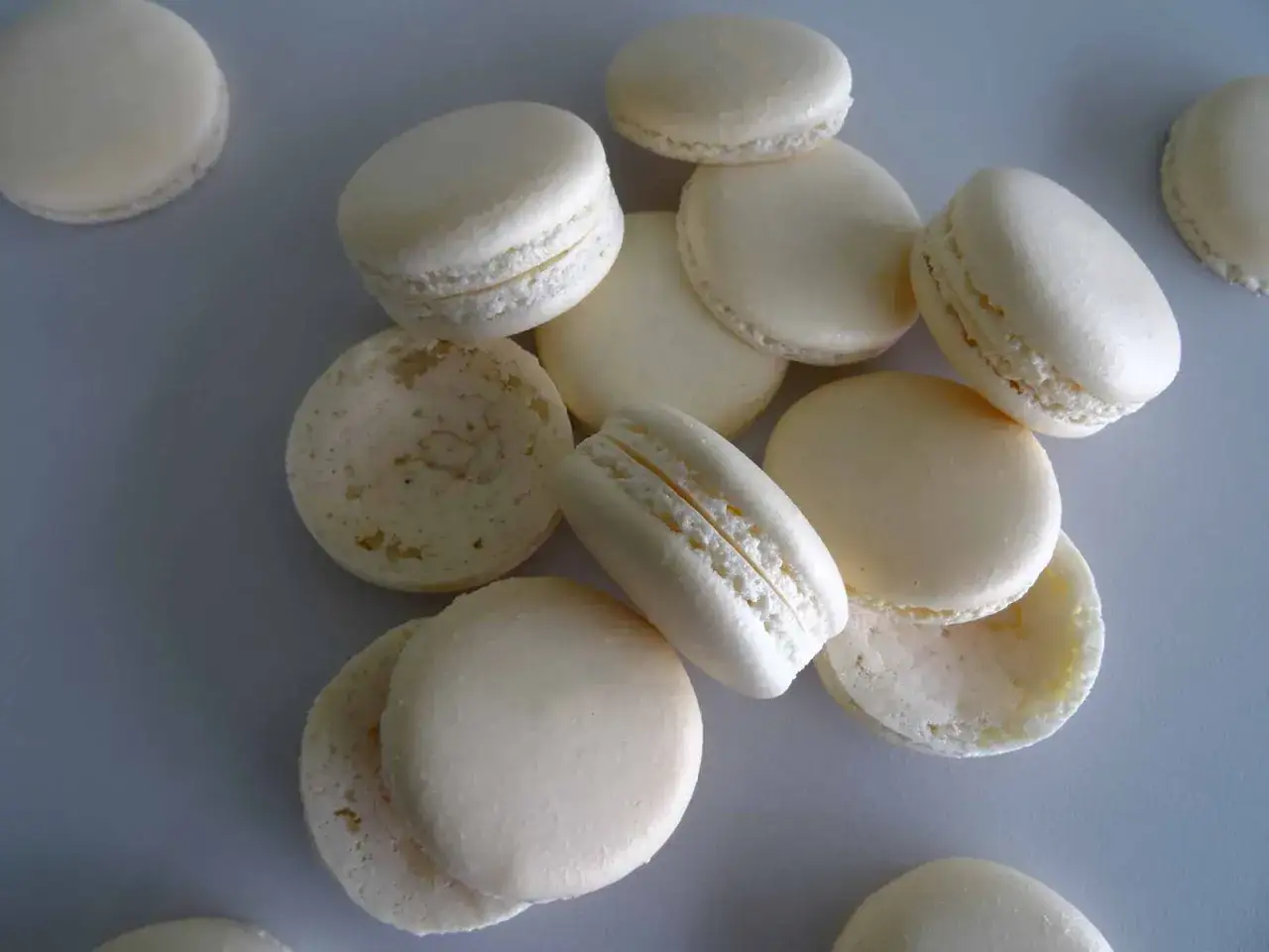 Un tas de macarons blancs, certains entiers, d'autres séparés, révèlent leur collerette macaron.