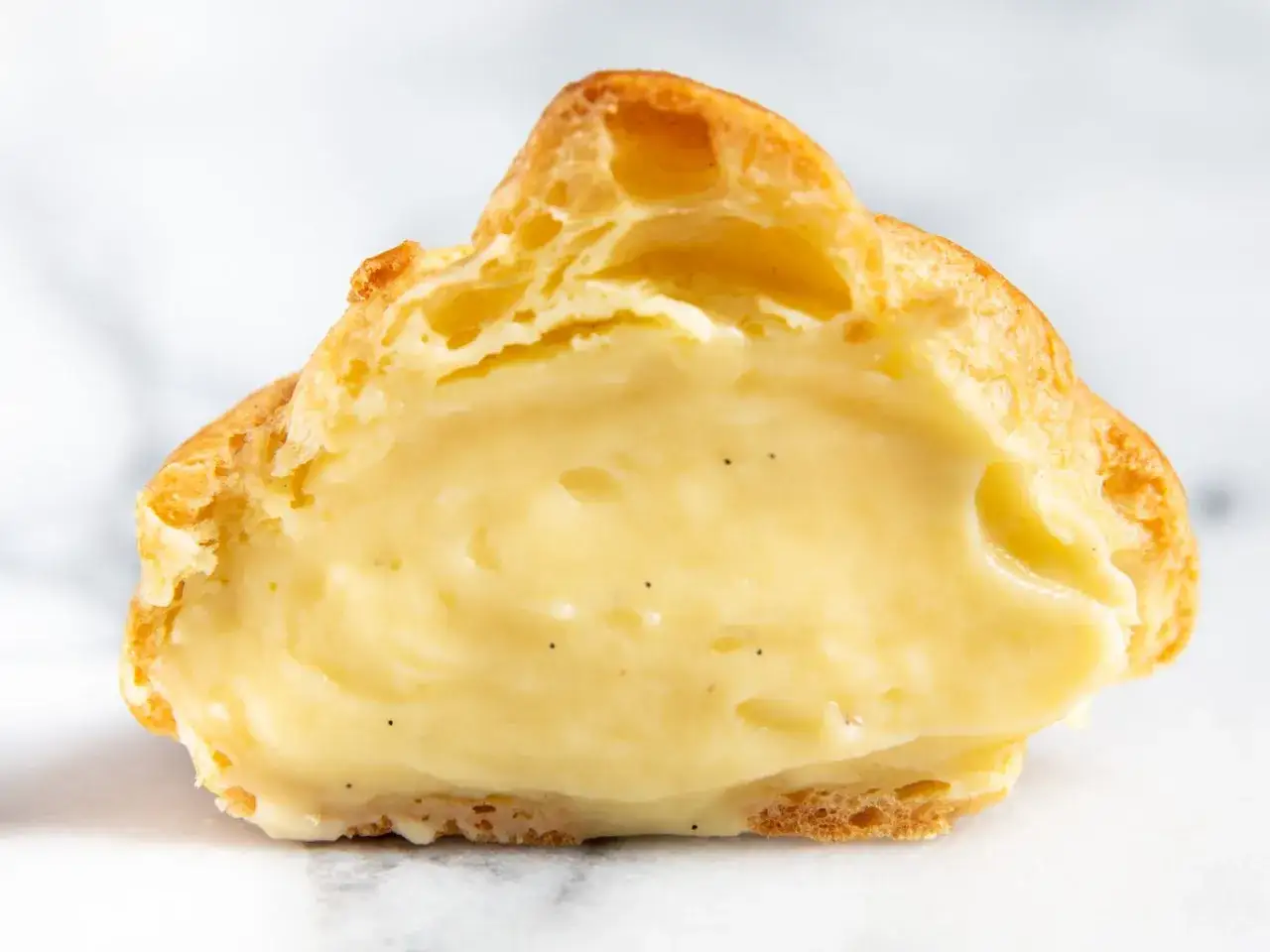 Une bouchée de délice : une pâte à choux dorée débordant de crème pâtissière mousseuse à la vanille.
