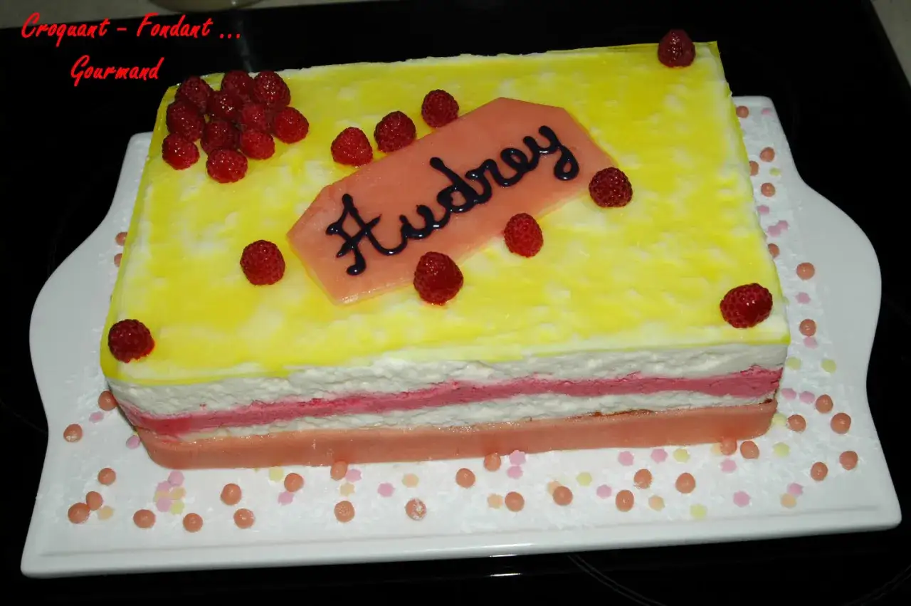 G&acirc;teau rectangulaire jaune et blanc, garni de framboises et d'une d&eacute;coration 