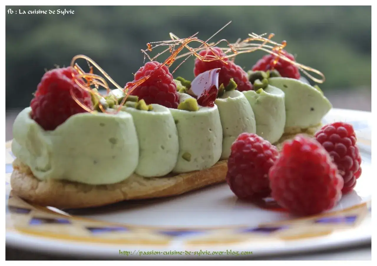 Éclair garni de chantilly pistache, framboises fraîches et fils de caramel. Un délice visuel et gustatif.
