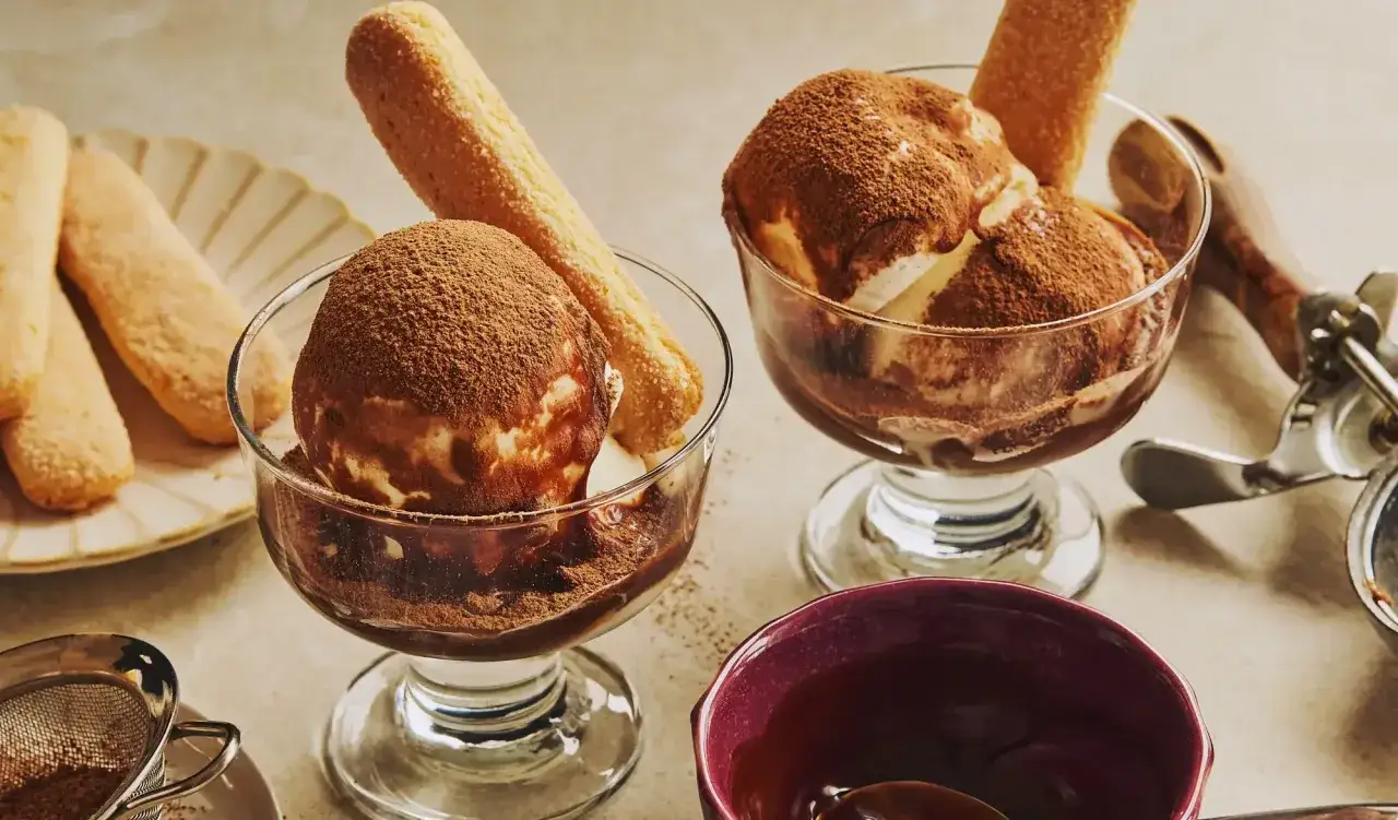 Deux coupes de glace tiramisu, saupoudrées de cacao, avec des biscuits à la cuillère.