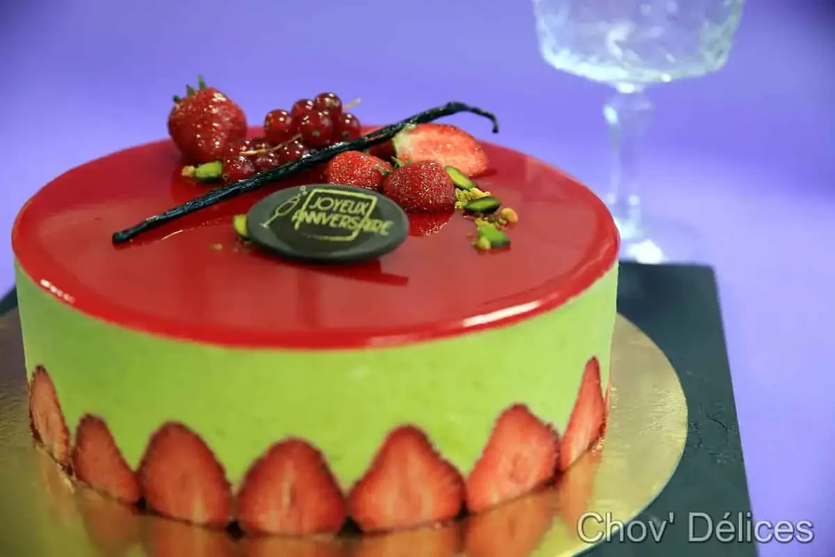 G&acirc;teau d'anniversaire vert pistache avec un gla&ccedil;age fraise brillant, d&eacute;cor&eacute; de fruits rouges et d'une inscription 