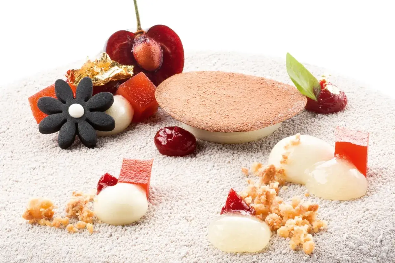 D&eacute;licieux dessert avec des fruits rouges, des cubes de gel&eacute;e rouge et des sph&egrave;res cr&eacute;meuses, le tout saupoudr&eacute; de cacao.