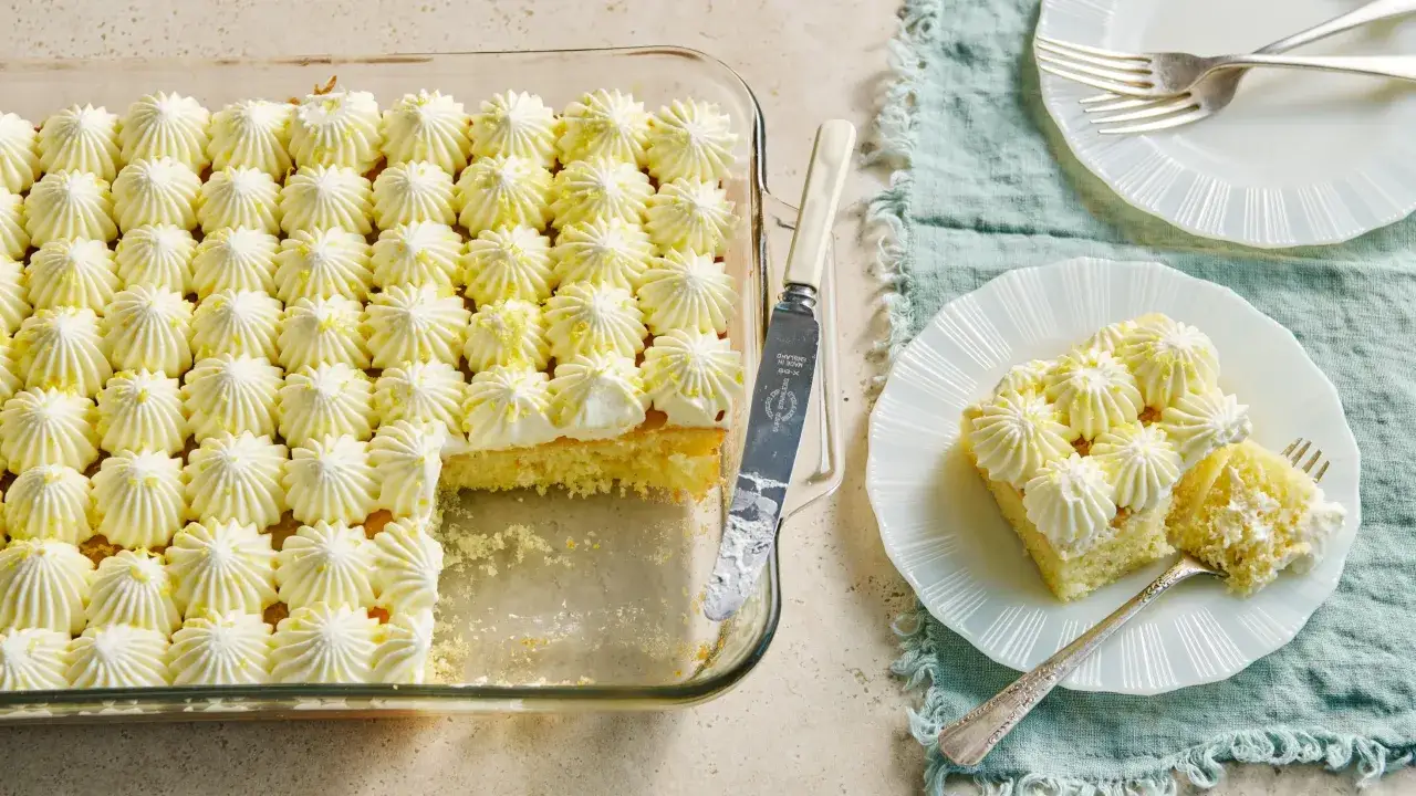 Un délicieux layer cake citron, garni de crème fouettée et de zestes de citron, prêt à être dégusté.