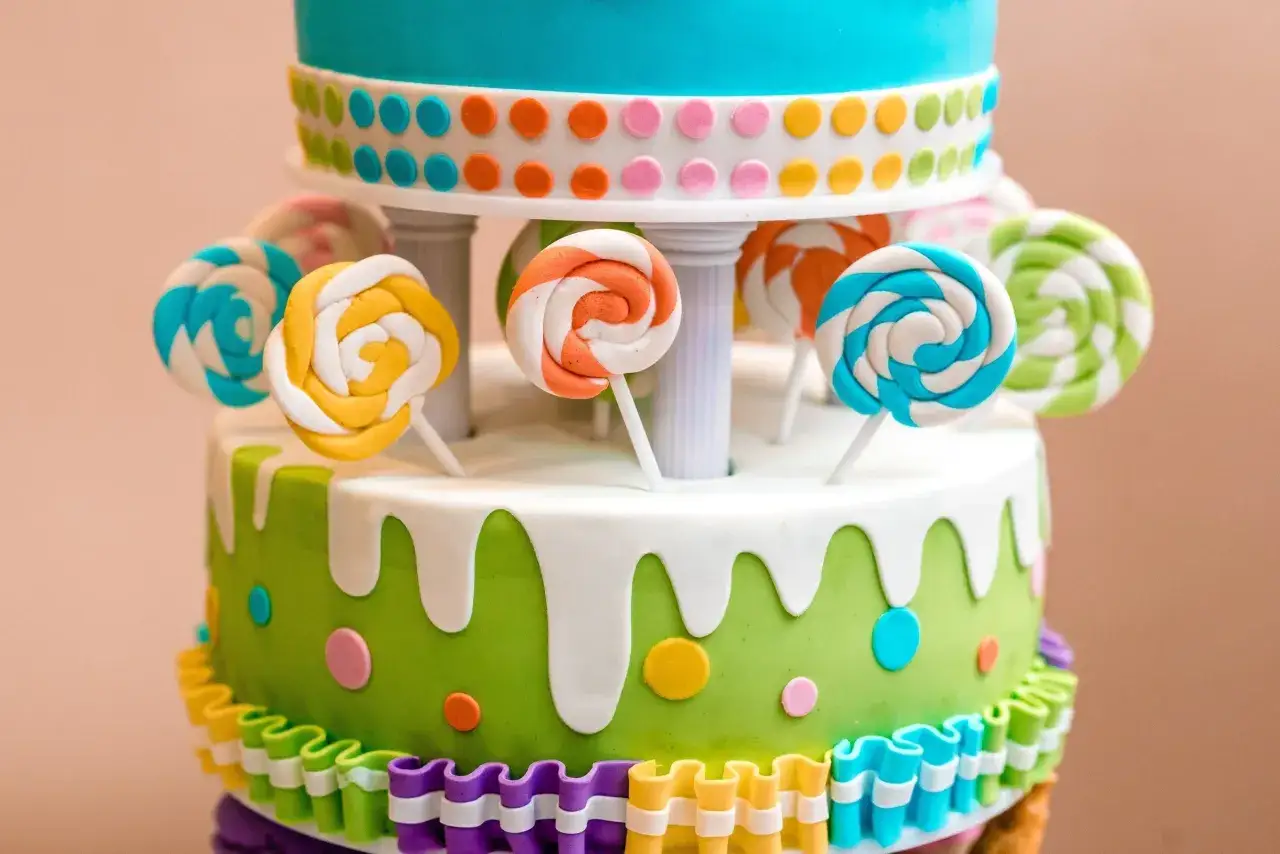 Un joyeux gâteau d'anniversaire en pâte à sucre, décoré de sucettes colorées et de pois vifs.