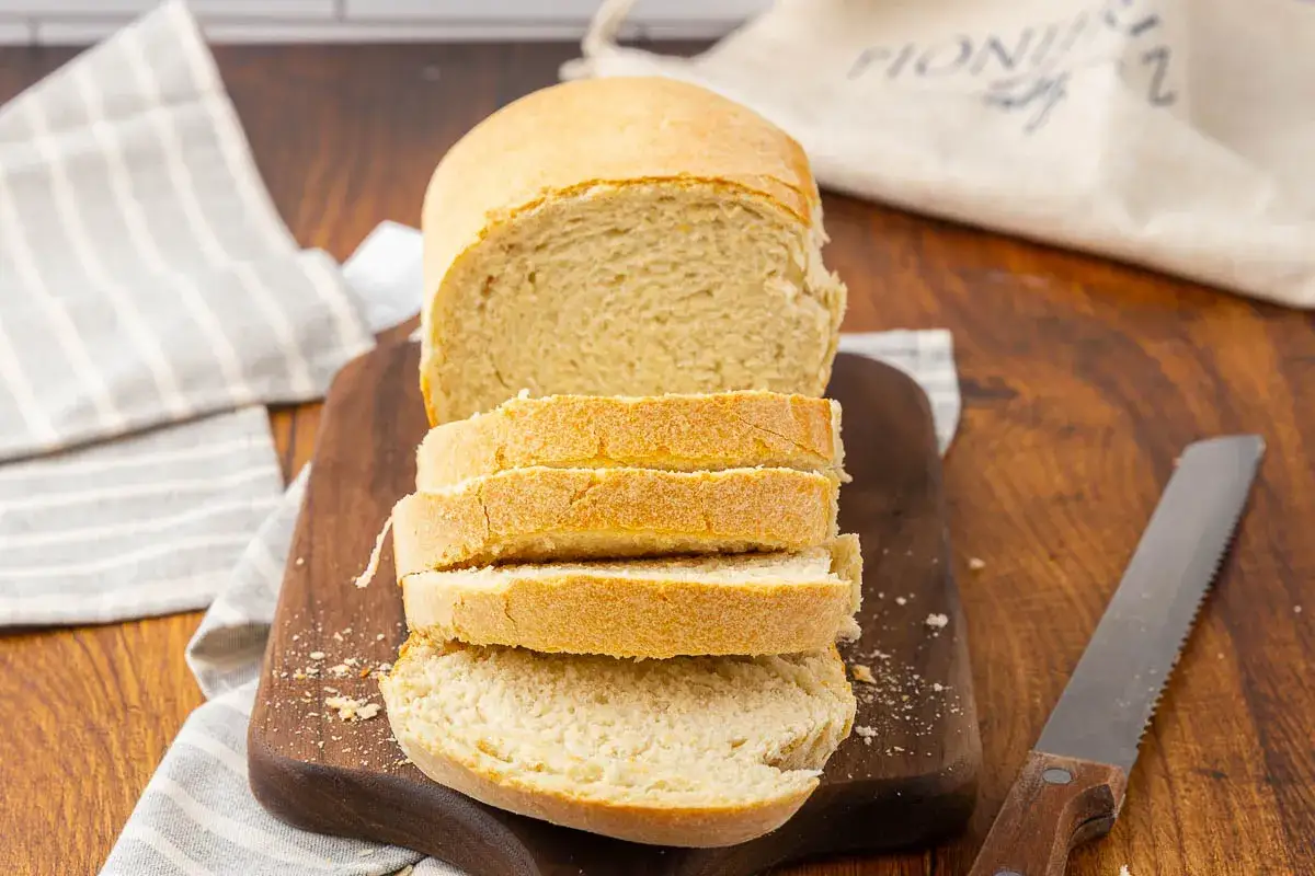 Pain de mie tranché sur une planche en bois, avec un couteau. Idéal pour savoir par quoi remplacer la levure boulangère.