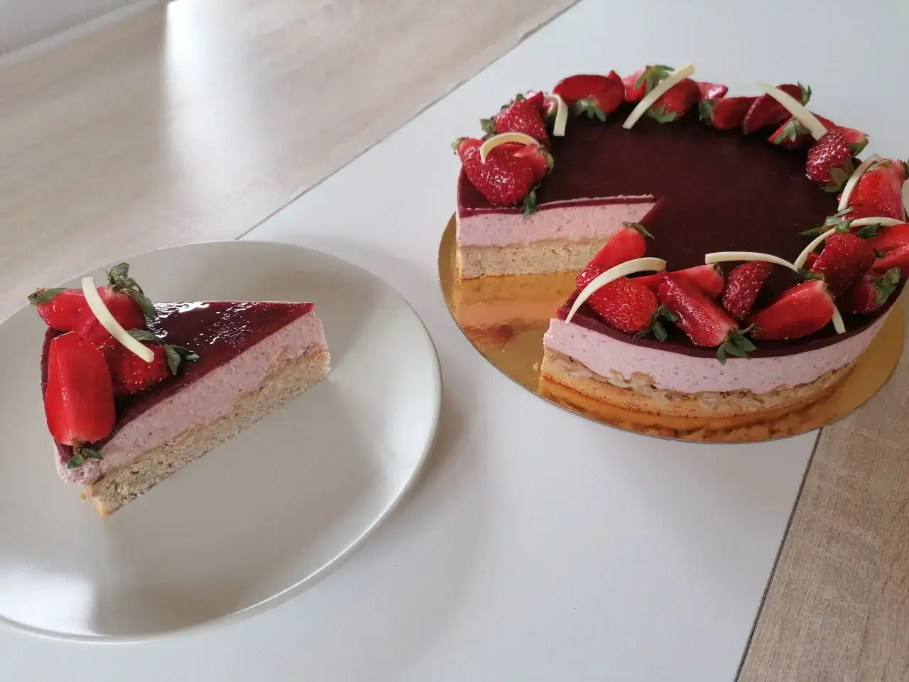 Un délicieux bavarois fraise, garni de fruits frais et de copeaux de chocolat blanc, avec une part servie sur une assiette.