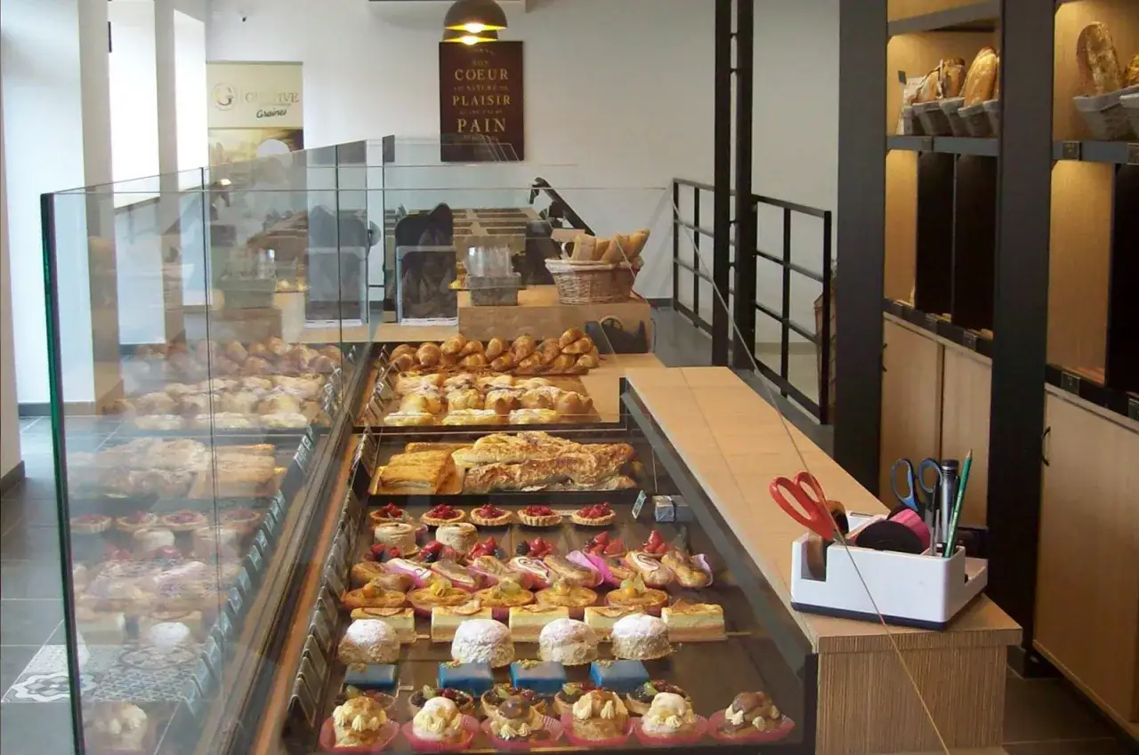 Vitrine d'une boulangerie regorgeant de pâtisseries. On y voit des croissants, des pains au chocolat, des tartes aux fruits et des petits gâteaux. Un nom gâteau chocolat boulangerie serait parfait pour décrire une de ces merveilles.