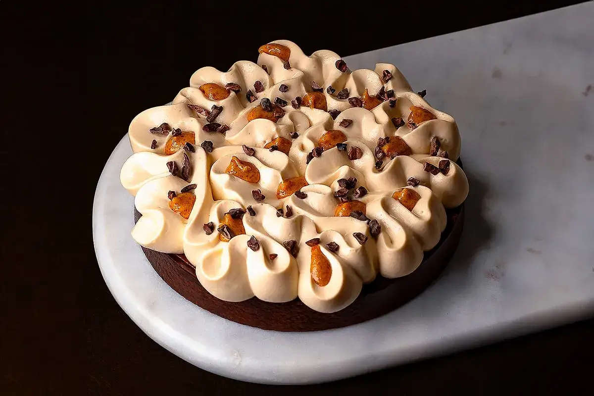 Tartelette au chocolat noir garnie d'une généreuse ganache caramel, parsemée de éclats de cacao et de morceaux de caramel.