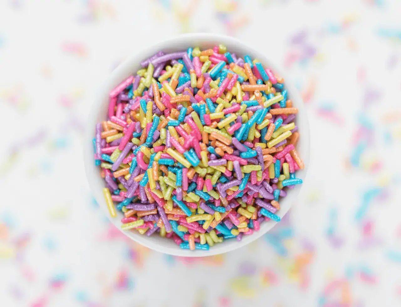 Un bol rempli de vermicelles colorés, parfaits pour une décoration cupcake facile et festive.