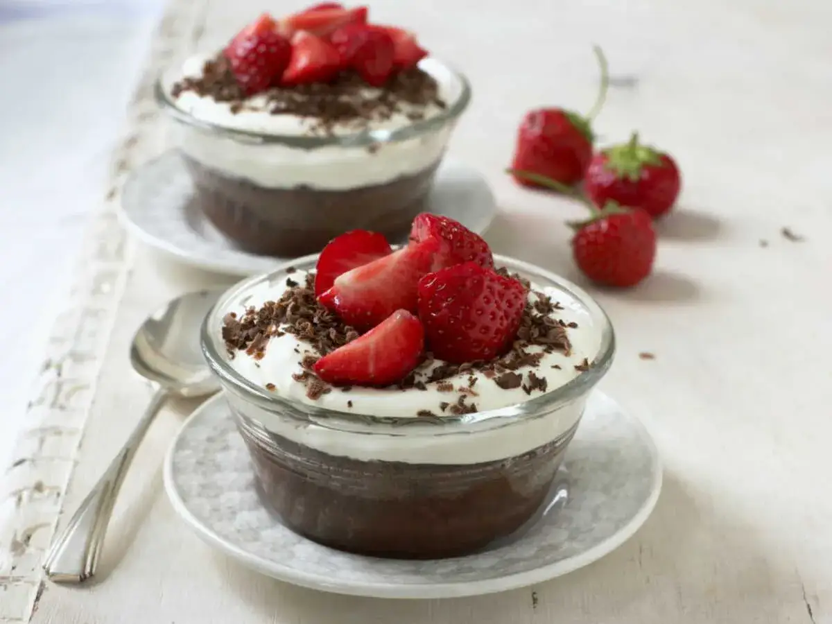 Deux verrines de mousse au chocolat, garnies de chantilly, fraises et copeaux de chocolat. Parfait pour rattraper une mousse au chocolat ratée !