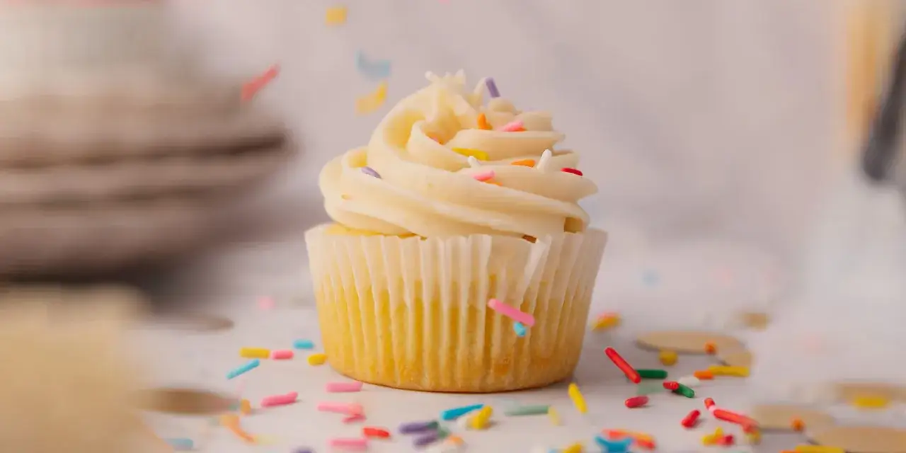 Un cupcake orn&eacute; d'un glacage cupcake vanille cr&eacute;meux, parsem&eacute; de vermicelles color&eacute;s tombant comme une pluie festive.