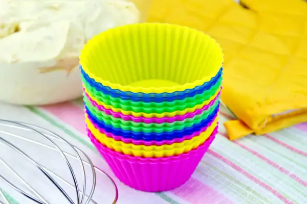 Pile de moules à cupcakes en silicone multicolores, prêts pour la pâtisserie. Apprenez comment nettoyer des moules en silicone pour qu'ils durent longtemps.