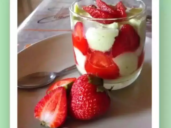 Un délicieux tiramisu pistache fraise, présenté en verrine avec des fraises fraîches sur le côté.