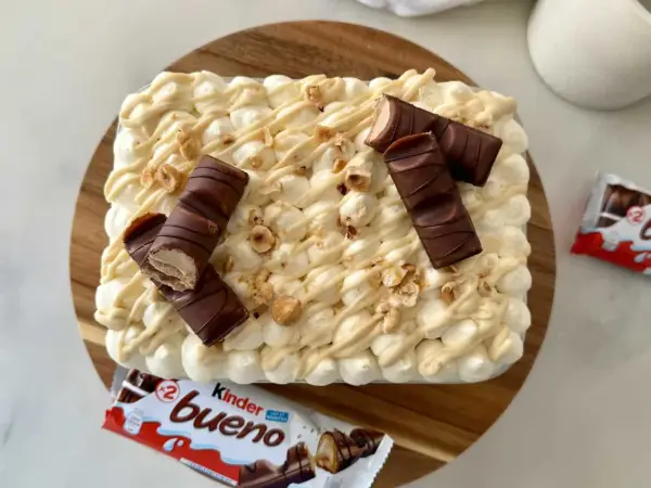 Un délicieux tiramisu Kinder Bueno, garni de morceaux de chocolat et de noisettes concassées. Un vrai régal pour les amateurs de chocolat !
