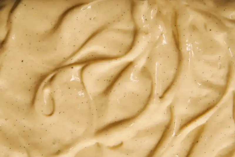 Texture onctueuse de crème pâtissière mousseuse, parsemée de points de vanille.